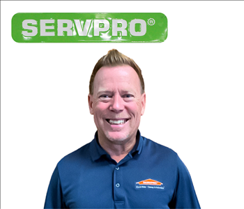 male employee standing under green SERVPRO sign