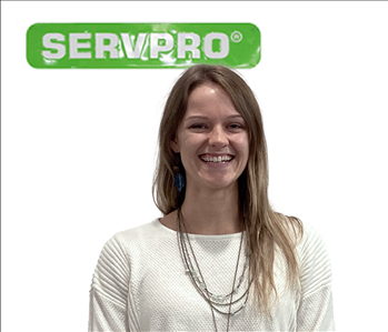 Rebecca Crow standing against a white wall with a SERVPRO® sign above her