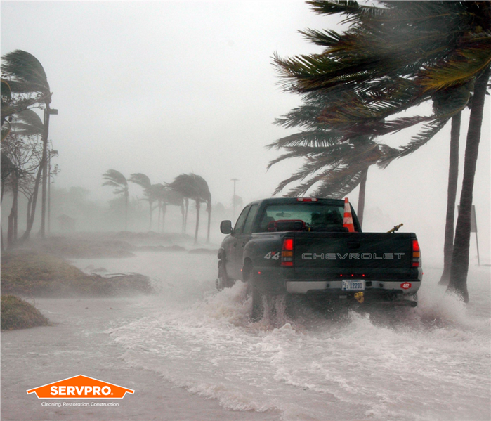 Truck driving through flooded streets during a hurricane in South Orlando, SERVPRO of South Orlando logo